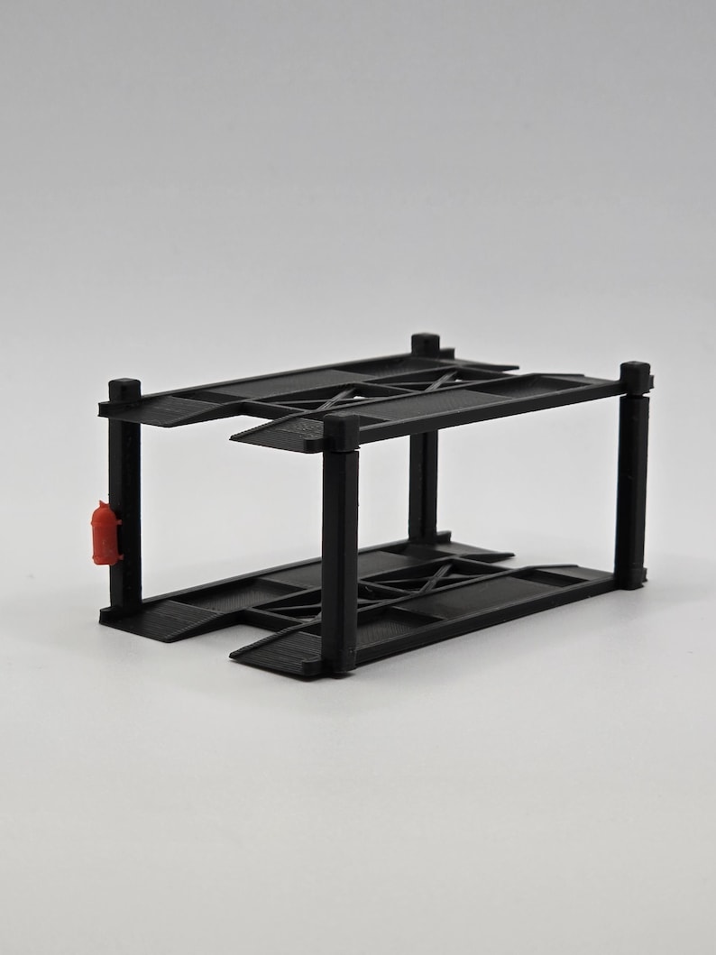 May include: Black metal two-tier car parking garage model. The garage has a red fire extinguisher on the side.