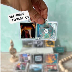 May include: A white ceramic mug with a black handle and the text "But First, Coffee" in a black, handwritten-style font. The mug is on a white surface.