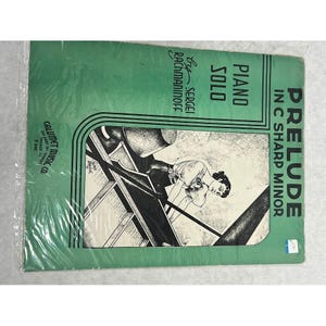 Op de afbeelding: Een groen bladmuziekomslag voor Prelude in C Sharp Minor van Sergei Rachmaninoff, uitgegeven door Calumet Music Co. De omslag bevat een zwart-witillustratie van een persoon die piano speelt, met zwarte tekst en drievoudige lijnen als rand.