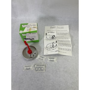 May include: A Dexter's Wool Cutter tool with a red handle and gray base, a green and white product box labeled 19-01065, an instructional paper sheet with diagrams, and several small rectangular blade packets in clear plastic sleeves.
