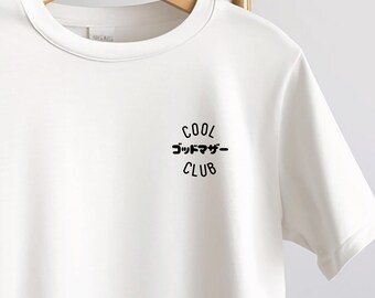 May include: White crew neck t-shirt with the text "COOL ゴッドマザー CLUB" printed in black. The shirt is hanging on a wooden hanger against a neutral background. The text is in both English and Japanese.