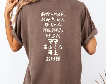 May include: A brown t-shirt with the Japanese words "おかあさん" (okaasan), "お母ちゃん" (okaachan), "母ちゃん" (hahachan), "お母さん" (okaasan), "お母さん" (okaasan), "ママ" (mama), "前行く" (maegiku), "母上" (bojou), and "お母様" (okaasama) printed on the back.