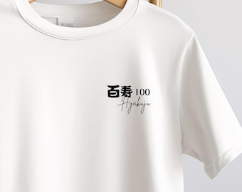 May include: White crew neck t-shirt with a black graphic on the left chest. The graphic includes Japanese characters, the number 100, and the word "Hyakuju" in a script font. The t-shirt is hanging on a wooden hanger.
