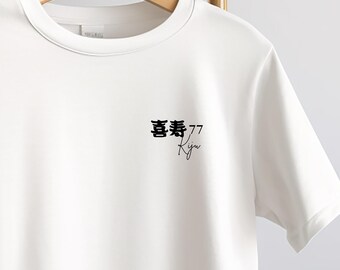 May include: White t-shirt with a crew neck, hanging on a wooden hanger. The shirt features black Japanese characters, the number 77, and the word "Kiju" in a script font, all printed on the front.