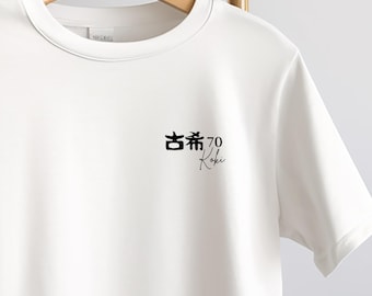 May include: White t-shirt with a crew neck, hanging on a wooden hanger. The shirt features black Japanese characters, the number 70, and the word "Koki" in a script font, all printed on the front.
