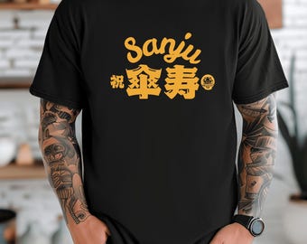 May include: Black t-shirt with the Japanese characters "Sanju" and "祝傘寿" in gold. The shirt has a crew neck and short sleeves. The fabric is garment-dyed for a soft color and vintage look.