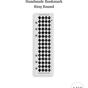 May include: A rectangular ring-bound bookmark featuring a black and white diamond pattern. The top text reads Month Ahead, and the bottom text reads Angel Kay Studio. The bookmark has six circular holes along the left side for ring binding.