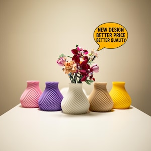 May include: Five colorful vases with a spiral design are arranged on a white surface. The vases are pink, purple, white, tan, and yellow. A bouquet of flowers sits in the white vase. A yellow speech bubble says "NEW DESIGN BETTER PRICE BETTER QUALITY."
