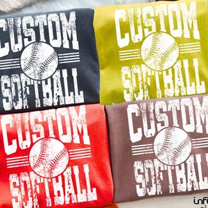 May include: Four custom softball shirts in various colors: charcoal, olive green, red, and brown. Each shirt features the words "CUSTOM SOFTBALL" in white block letters with a distressed softball graphic in the center.