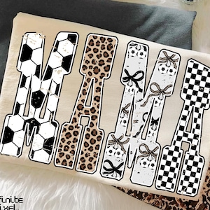 May include: Cream-colored t-shirt with the word "MAMA" in large, bold letters. Each letter features a different pattern: soccer balls, leopard print, soccer balls with bows, and a black and white checkered pattern. The Infinite Pixel Studio logo is in the bottom left.