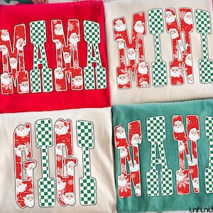 May include: Four folded t-shirts with Christmas-themed text. The shirts are red, cream, and green. Each shirt has a different word: "MAMA", "MINI", "GIGI", and "NANA". The letters are red with a Santa Claus pattern and green and white checkered accents.