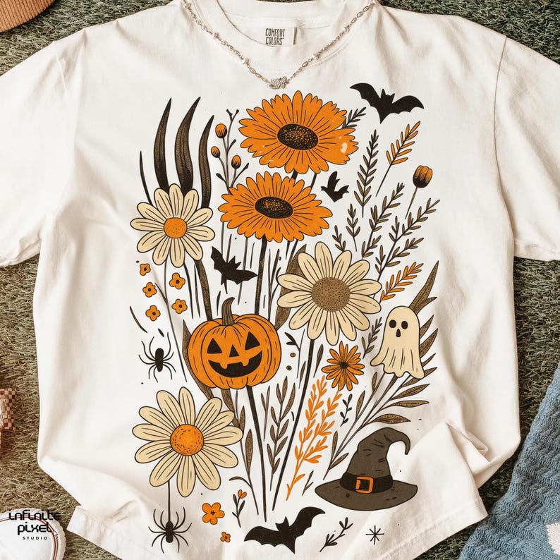 Peut inclure: T-shirt cr&egrave;me avec un motif floral d'Halloween. Le graphisme comprend des tournesols orange, des marguerites, une citrouille sculpt&eacute;e, des chauves-souris, un fant&ocirc;me et un chapeau de sorci&egrave;re. Le t-shirt porte l'inscription "Comfort Colors".