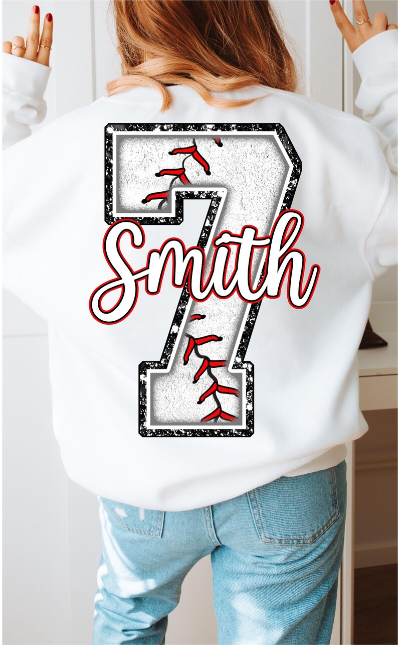Pu&ograve; includere: Felpa bianca con un numero 7 nero e bianco a tema baseball con cuciture rosse. Il nome "Smith" &egrave; scritto in corsivo bianco sopra il numero.