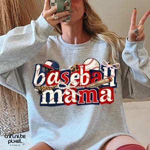 May include: A light gray sweatshirt with the words "Baseball Mama" in red, white, and blue, with baseball-themed graphics. The design includes a baseball, bat, and a baseball cap.