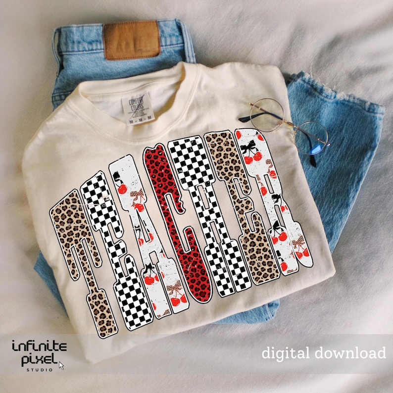 May include: Cream-colored t-shirt with the word "TEACHER" in a unique design. The letters feature leopard print, checkered patterns, and cherry illustrations. The shirt is laid on top of blue jeans.