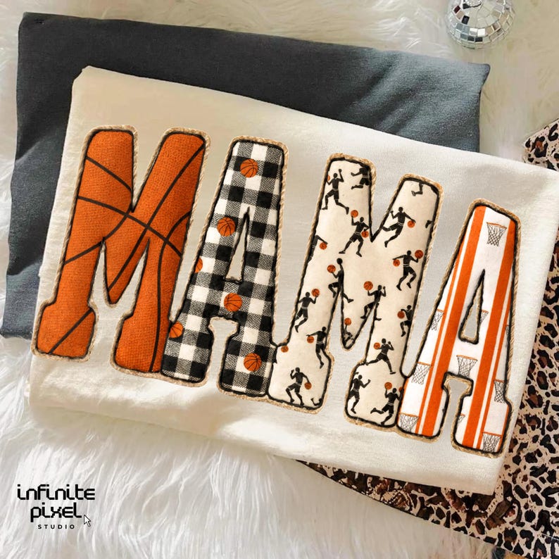 Puede incluir: Sudadera crema con la palabra "MAMA" en letras grandes y decorativas. La "M" es naranja con l&iacute;neas de baloncesto, la primera "A" es a cuadros blancos y negros, la segunda "M" tiene siluetas de jugadores de baloncesto y la &uacute;ltima "A" es naranja con rayas de red de baloncesto.