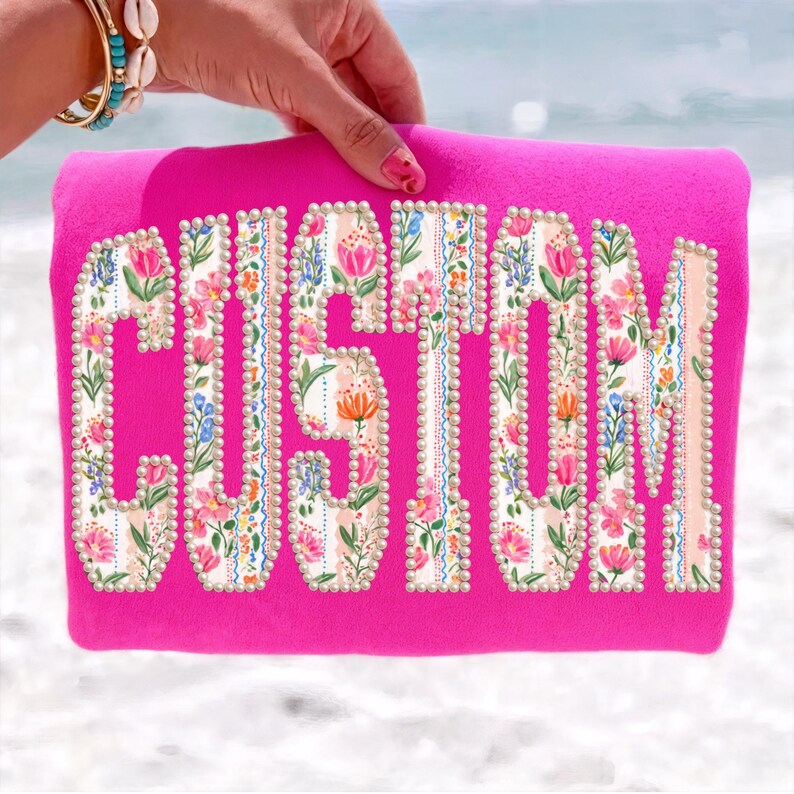 Puede incluir: Un bolso tote rosa intenso con la palabra "CUSTOM" en letras grandes y florales. Las letras est&aacute;n rellenas con un patr&oacute;n de flores rosas, naranjas y azules y delineadas con peque&ntilde;as cuentas perladas.
