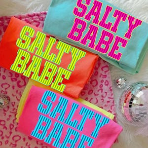 May include: A set of three ceramic mugs with a speckled, matte finish. Each mug features a different color: light blue, cream, and gray. The mugs have a simple, modern design and a comfortable handle.