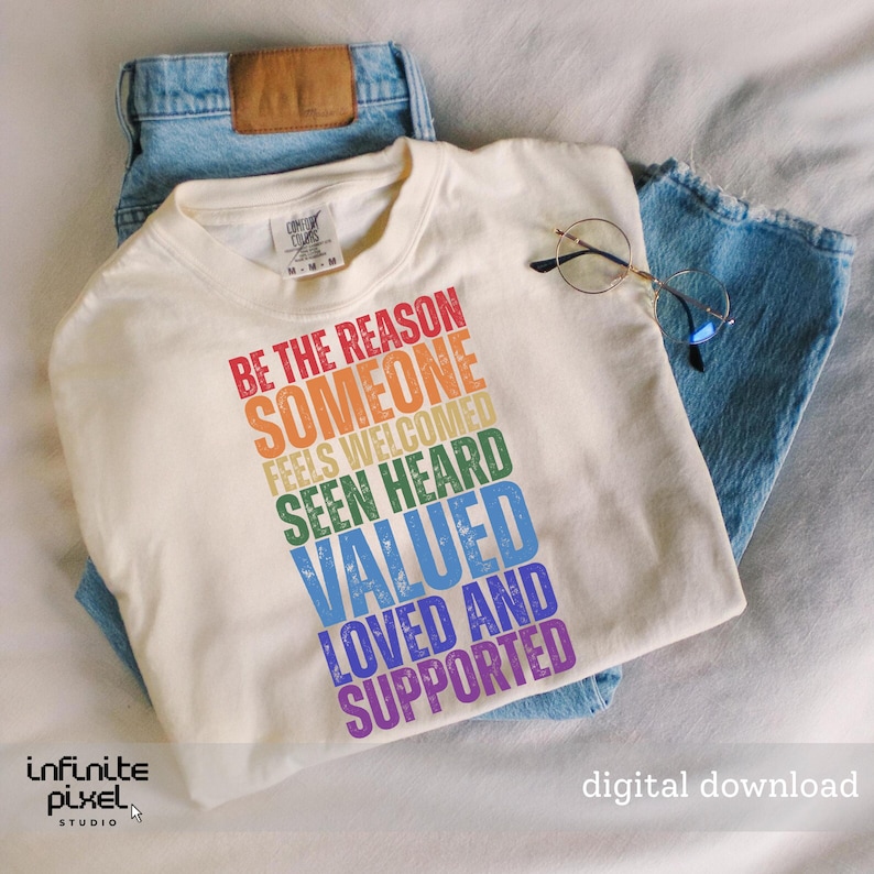 Puede incluir: Camiseta color crema con el texto "BE THE REASON SOMEONE FEELS WELCOMED SEEN HEARD VALUED LOVED AND SUPPORTED" en colores arco&iacute;ris. La camiseta se combina con unos vaqueros azules y gafas de montura redonda.