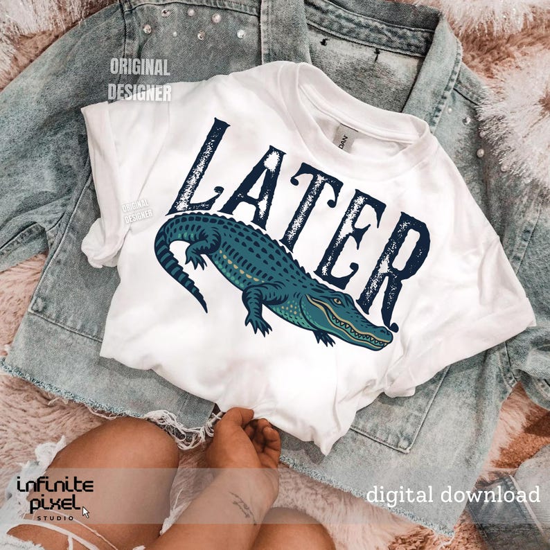Pode incluir: Camiseta branca com um gr&aacute;fico de um jacar&eacute; azul e a palavra "Later" em texto preto.