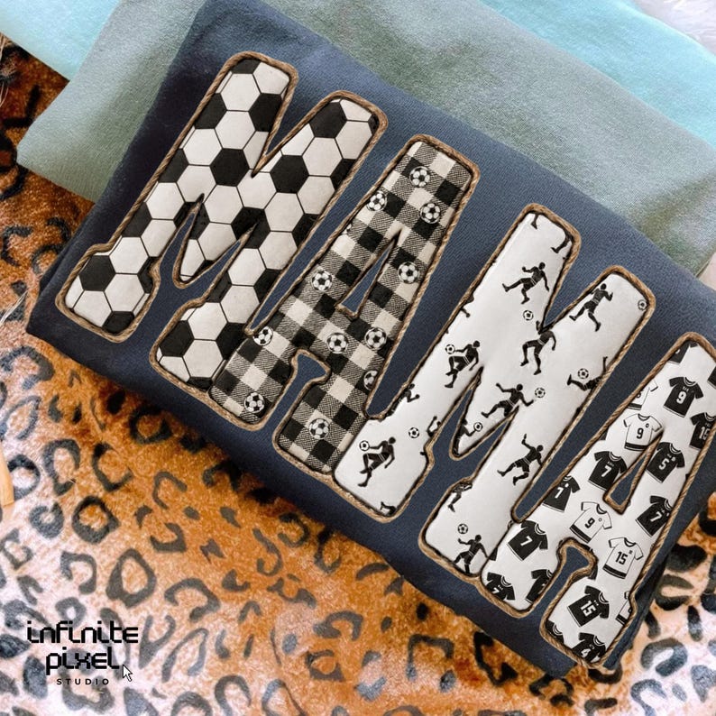 May include: A navy blue decorative pillow with the word "MAMA" appliqued on the front. The letters are in a variety of patterns, including soccer balls, black and white plaid, soccer player silhouettes, and soccer jerseys. The letters are outlined with a brown rope trim.