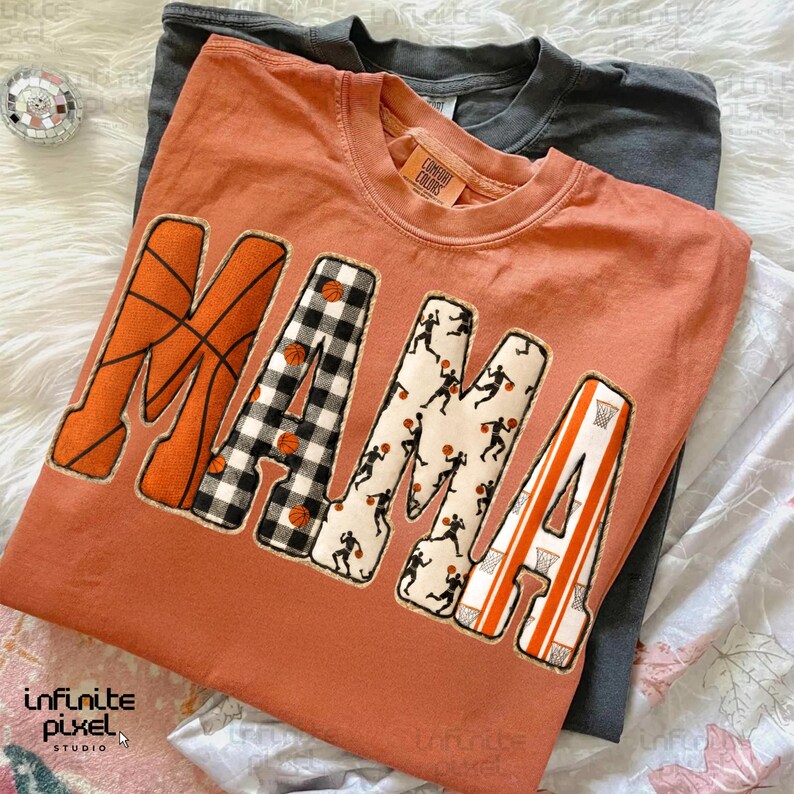 Puede incluir: Una camiseta de color naranja quemado con la palabra "MAMA" en un tema de baloncesto. La "M" es naranja con l&iacute;neas de baloncesto, la "A" es a cuadros blancos y negros, la segunda "M" tiene siluetas de jugadores de baloncesto y la "A" final tiene rayas naranjas y blancas.