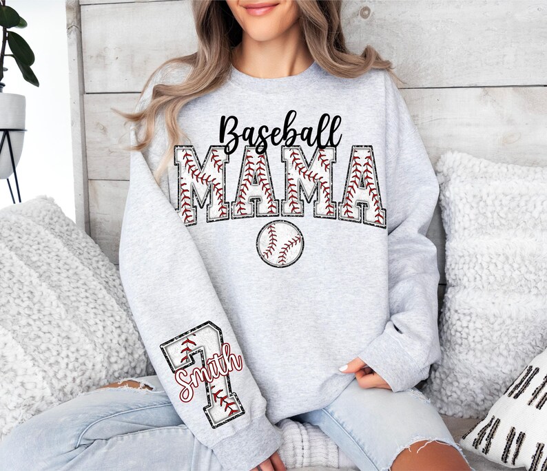 Pu&ograve; includere: Felpa grigia con il testo "Baseball Mama" in nero con una grafica di baseball. La manica ha una grafica di baseball con il testo "Smith" in rosso.
