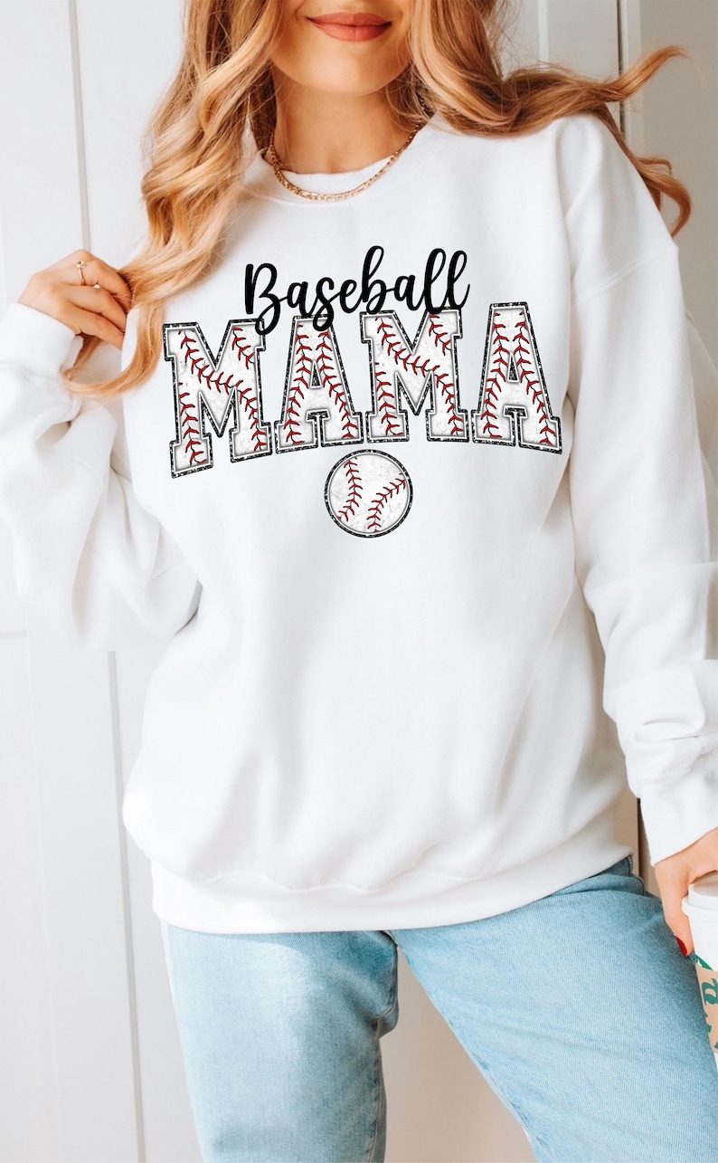 Pu&ograve; includere: Felpa bianca con il testo "Baseball Mama" in lettere nere con un design a punto di baseball rosso. Sotto il testo c'&egrave; una palla da baseball rossa con cuciture bianche.