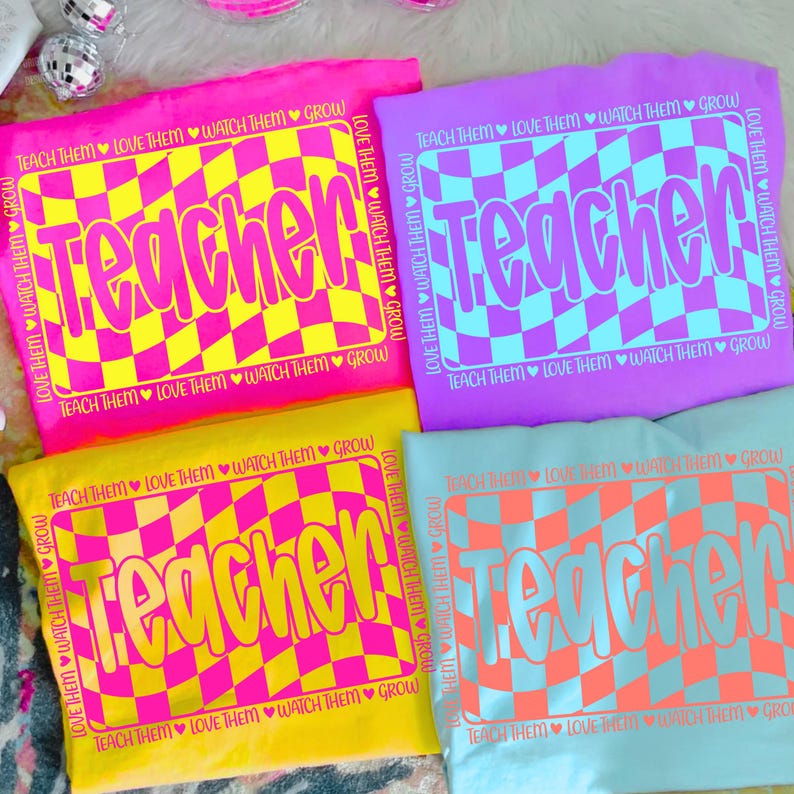May include: Four colorful t-shirts with the word "Teacher" in a wavy checkerboard design. The shirts are pink, purple, yellow, and light blue. Each shirt has the phrase "Teach Them, Love Them, Watch Them Grow."
