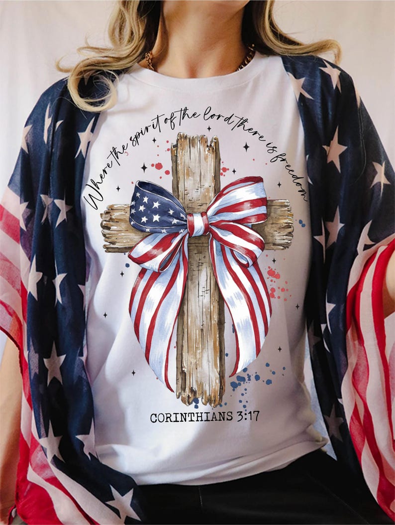 K&ouml;nnte beinhalten: Wei&szlig;es T-Shirt mit einem Holzkreuz und einer rot-wei&szlig;-blauen Schleife. Die Schleife ist aus Stoff mit dem Muster der amerikanischen Flagge. Der Text "Where the spirit of the Lord there is freedom" ist um das Kreuz herum geschrieben. Der Text "Corinthians 3:17" ist unter dem Kreuz geschrieben.