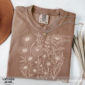 May include: A brown Comfort Colors t-shirt with a white floral design. The shirt has a crew neck and short sleeves. A silver necklace with a pendant rests on the shirt. The words "Original Designer" and "Digital Download" are visible.