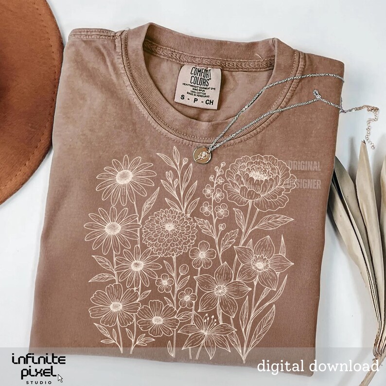 May include: A brown Comfort Colors t-shirt with a white floral design. The shirt has a crew neck and short sleeves. A silver necklace with a pendant rests on the shirt. The words "Original Designer" and "Digital Download" are visible.