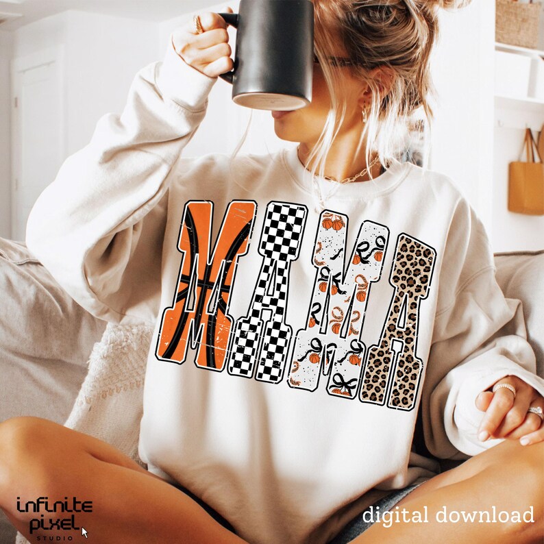 Puede incluir: Sudadera color crema con la palabra "MAMA" en un dise&ntilde;o &uacute;nico. La "M" presenta una pelota de baloncesto, la primera "A" tiene un patr&oacute;n de cuadros blancos y negros, la segunda "M" tiene un patr&oacute;n de baloncesto y lazo, y la &uacute;ltima "A" tiene un estampado de leopardo.