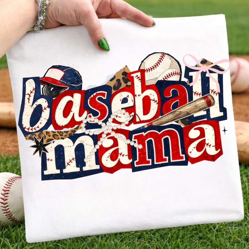 May include: White t-shirt with a baseball-themed design. The design features the words "Baseball Mama" in red and blue, along with a baseball, bat, and helmet. A pearl necklace and a pink bow add decorative elements.