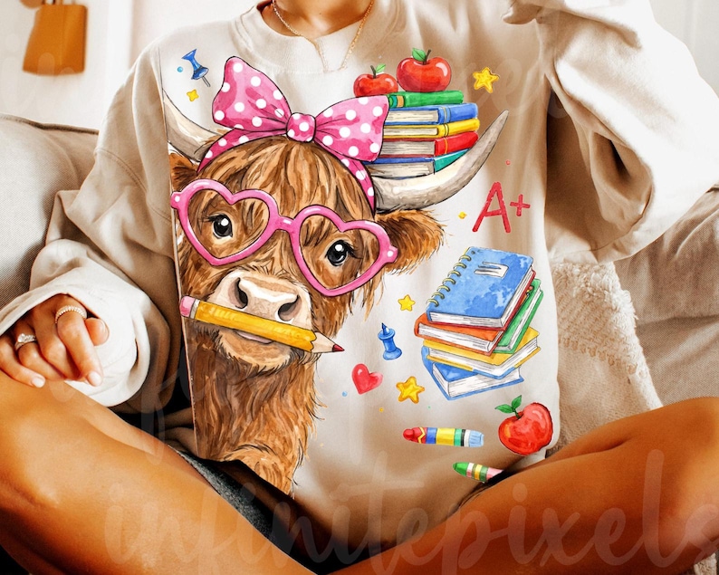 Pu&ograve; includere: Una felpa beige con un cartone animato di una mucca delle Highlands con occhiali rosa a forma di cuore e un fiocco a pois. La mucca tiene in bocca una matita, con libri, mele e la lettera "A+" stampata. Un divertente tema di ritorno a scuola.