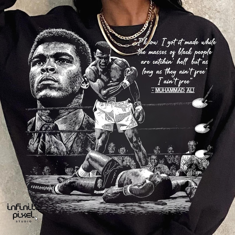 May include: Black sweatshirt featuring a graphic of Muhammad Ali in a boxing ring, with a quote. The design includes illustrations of Ali in different poses, with a crowd in the background. The sweatshirt has the text "Infinite Pixel Studio".