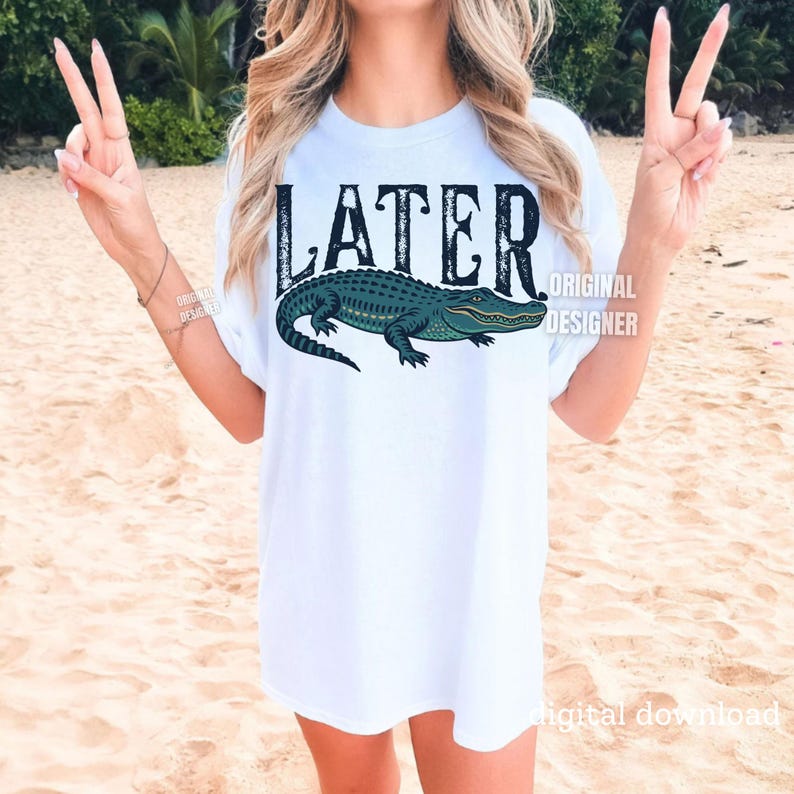 Pode incluir: Camiseta branca com um gr&aacute;fico de um jacar&eacute; verde e a palavra "LATER" em letras pretas desgastadas.