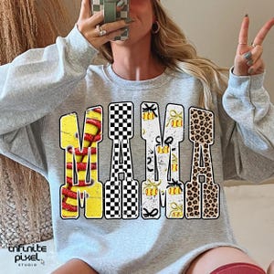 May include: A light gray sweatshirt with the word "MAMA" in large, colorful letters. The "M" is yellow with red stripes, the "A" is black and white checkered, the second "M" is white with yellow bows, and the final "A" is leopard print.
