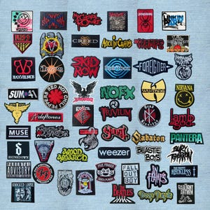 May include: A collection of various embroidered fabric patches featuring logos and text from numerous musical bands and artists, arranged in a grid pattern on a light blue denim background. The patches display diverse shapes, colours, and fonts.