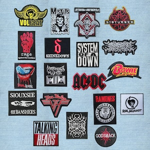 Puede incluir: Una colección de veinte parches de tela bordados con varios logotipos de bandas y diseños gráficos en negro, blanco, rojo y amarillo. Los parches incluyen nombres como Volbeat, Misfits, Avenged Sevenfold, Disturbed, Rage Against the Machine, Shinedown, System of a Down, Falling in Reverse, Motionless in White, AC/DC, Bowie, Siouxsie and the Banshees, Van Halen, Ramones, Rise Against, Talking Heads y Godsmack.
