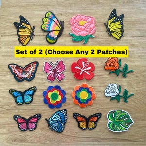 Könnte beinhalten: Eine Sammlung von gestickten Aufnähern mit verschiedenen Schmetterlingen, Blumen und Blättern in leuchtenden Farben. Der Text "Set of 2 (Choose Any 2 Patches)" steht in der Mitte. Die Motive umfassen orange, blaue, rosa und gelbe Schmetterlinge.