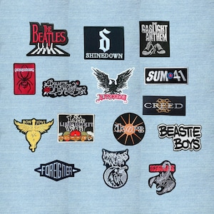 May include: A collection of fifteen embroidered fabric patches featuring various band logos and graphic designs, including The Beatles, Shinedown, The Gaslight Anthem, Bullet for My Valentine, Alter Bridge, Sum 41, Creed, Bon Jovi, The Doors, and Scorpions.