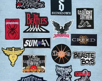 Puede incluir: Una colección de parches de tela bordados con varios logotipos de bandas y diseños gráficos, incluyendo Bullet for My Valentine, The Beatles, Shinedown, The Gaslight Anthem, In This Moment, Alter Bridge, Sum 41, Creed, Bon Jovi, The Doors, Beastie Boys, Limp Bizkit, Foreigner, Motionless in White y Scorpions.
