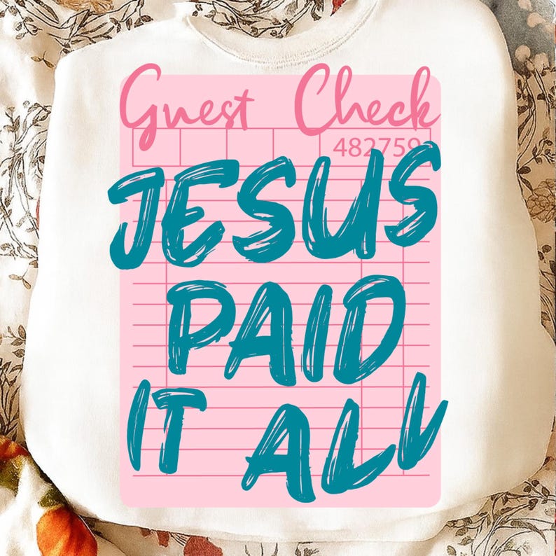 May include: White sweatshirt with a pink and teal graphic. The graphic resembles a guest check and reads "Guest Check" in pink, and "JESUS PAID IT ALL" in teal. The sweatshirt is likely made of a soft material.