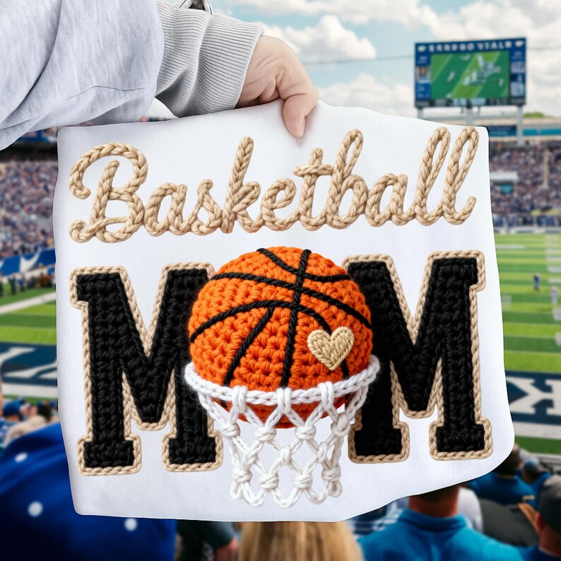 May include: White sign with the words "Basketball Mom" in a rope-like font. The "MOM" is in black with a basketball and net design. The basketball is orange and black with a small heart.