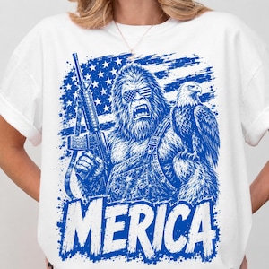 Könnte beinhalten: Ein weißes T-Shirt mit einer blauen Grafik eines Bigfoot, der eine Sonnenbrille im US-Flaggen-Design und eine Latzhose trägt, ein Gewehr hält und einen Weißkopfseeadler auf dem Arm hat. Darunter steht der Text MERICA.