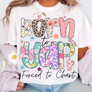 May include: White t-shirt with a colorful graphic design. The design includes the words "Born to Yap, Forced to Chart" in various fonts and patterns, including floral, leopard print, and a syringe. Additional elements include a nurse's hat, bow, and stars.