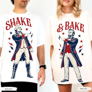 Pode incluir: Duas camisetas brancas com figuras históricas. A camiseta da esquerda mostra George Washington com o texto SHAKE. A da direita mostra Abraham Lincoln com o texto & BAKE. Ambos os designs incluem estrelas e raios vermelhos e azuis.