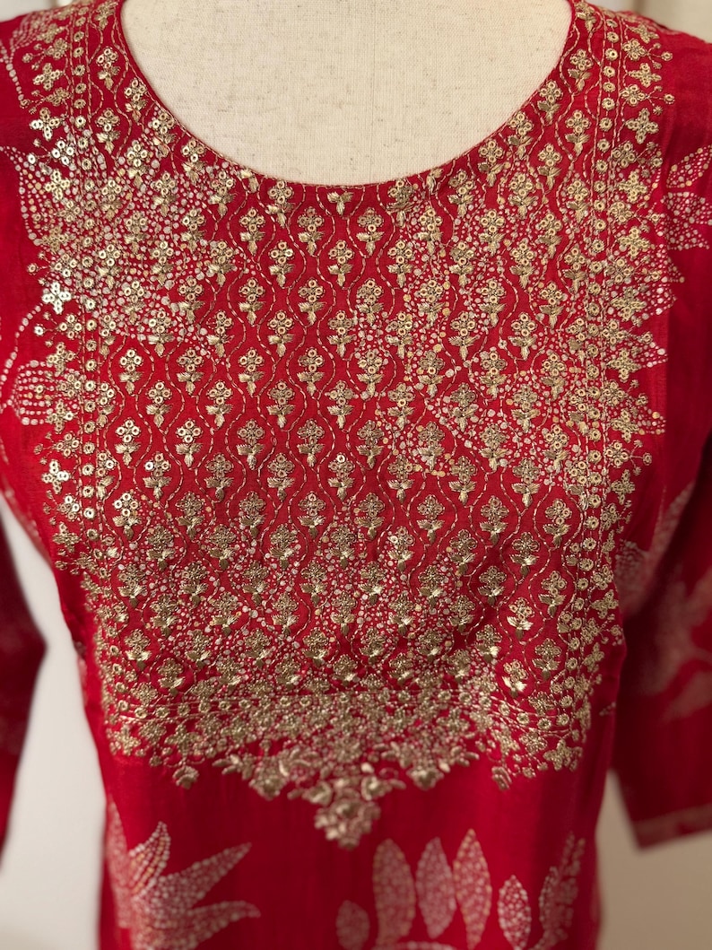 May include: Red kurta with gold embroidery and sequins. The embroidery features a floral pattern.