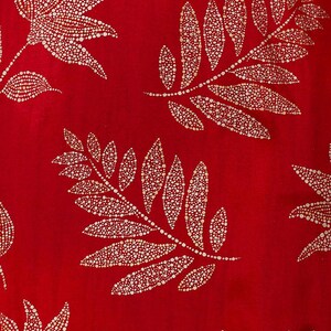 May include: Red fabric with a repeating pattern of gold leaf branches. The branches are made up of small, round dots.